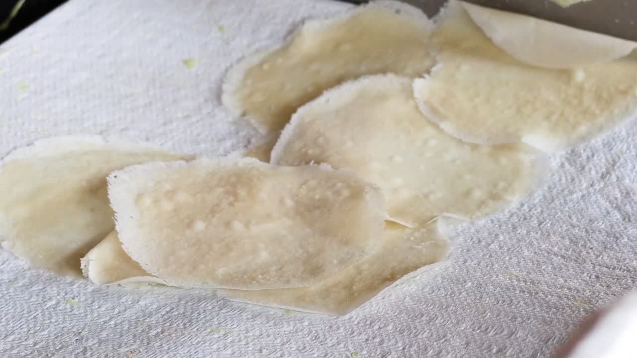 Hands carefully layer thin crepe sheets on a white absorbent towel, ensuring even spacing and gentle handling.