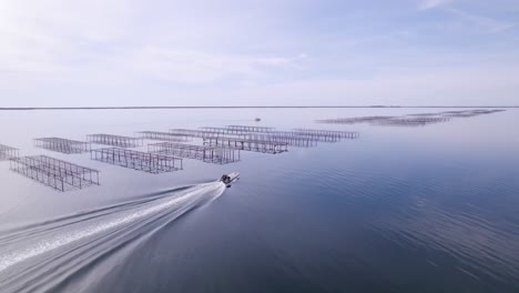 Aerial-landscape-shot-of-a-motorboat-sailing-near-cristal-clear-waters-at-Thau-Lagoon-in-Sete,-France