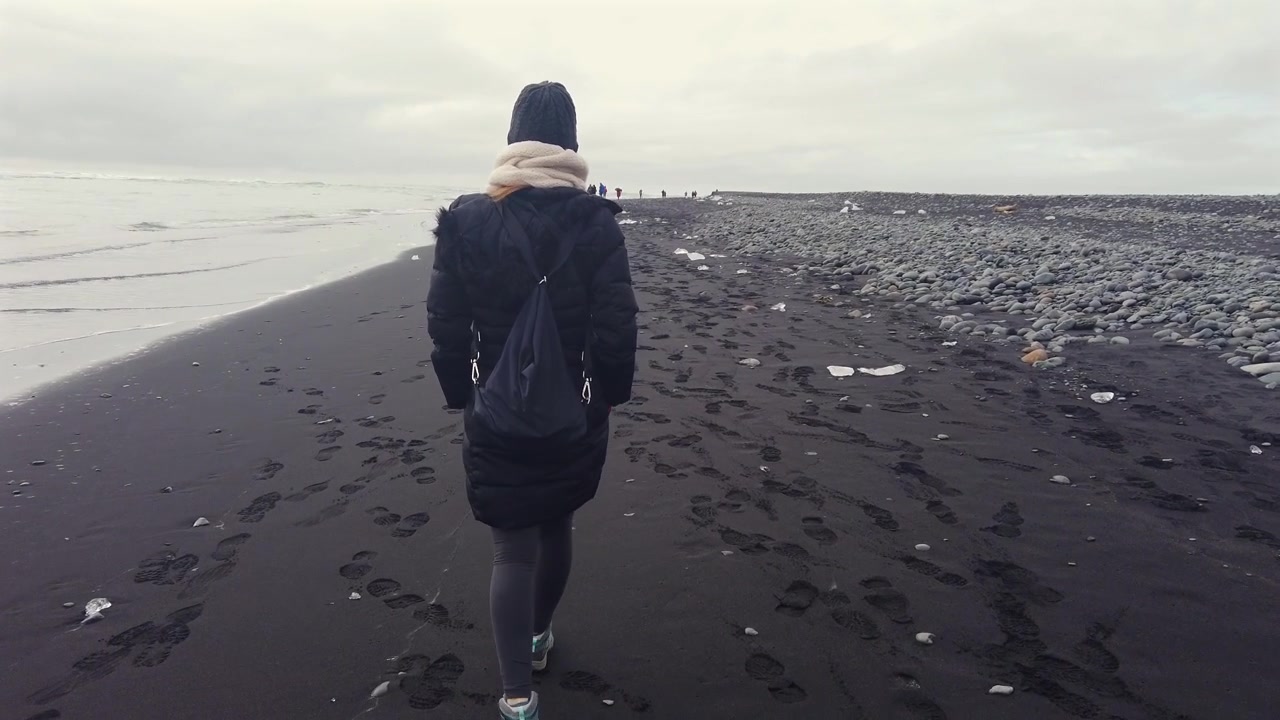 Seguendo una donna solitaria che cammina lungo l'iconica spiaggia dei diamanti in Islanda, lasciando impronte nella sabbia.