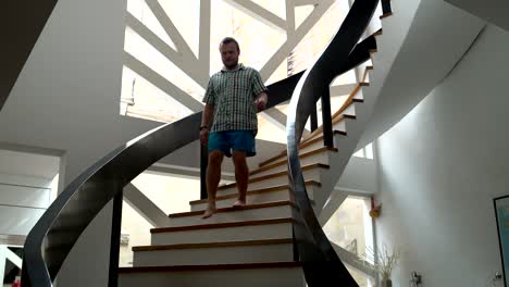a man descends the stairs from the top floor of the house