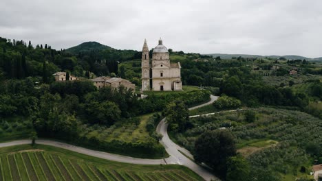 drone shot flying by italy's sanctuary of the madonna di san biagio amidst a green countryside backdrop