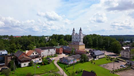 wide aerial view of traditional homes in vibrant colors leading to the prominent church and forest edge. shot at zarasai, lithuania (zarasai, lietuva)