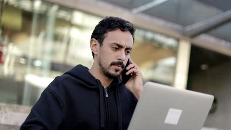hombre serio usando portátil y teléfono inteligente