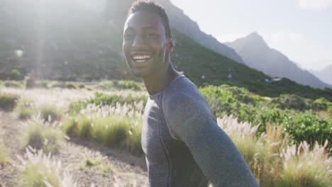 portrait of smiling african american man exercising resting during a run in countryside