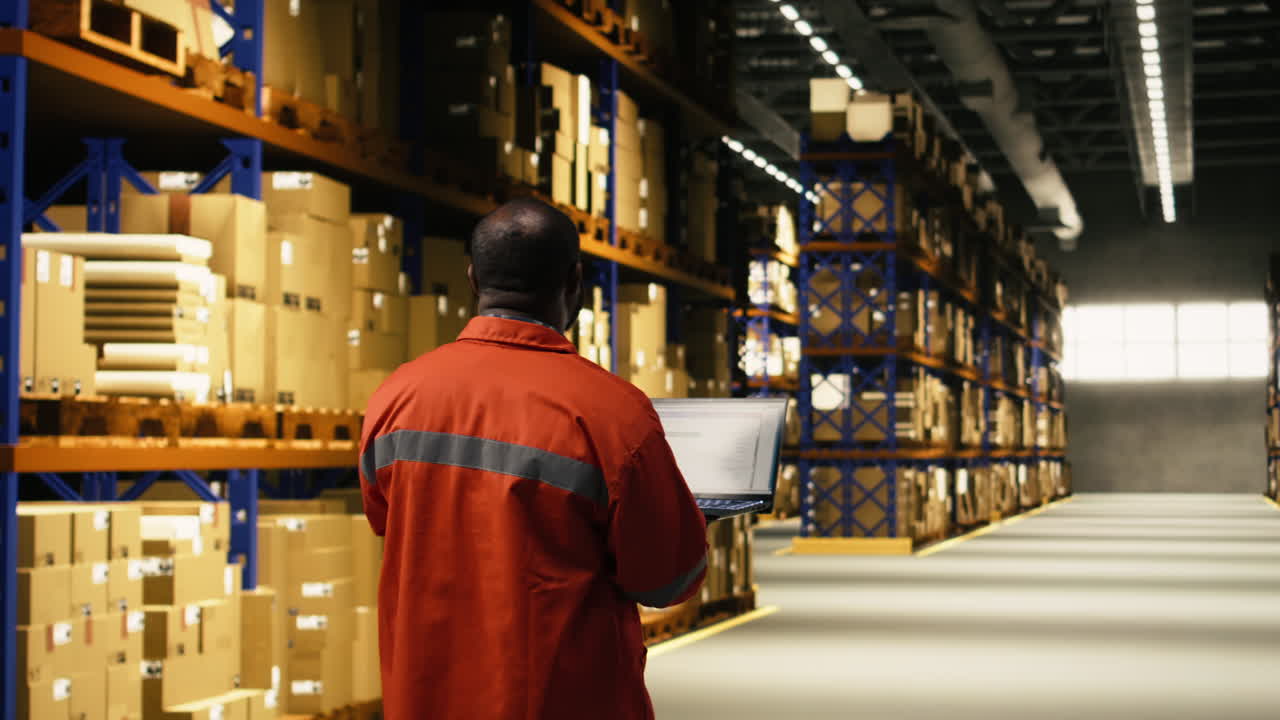 African american staff overseeing cargo on laptop in large business facility