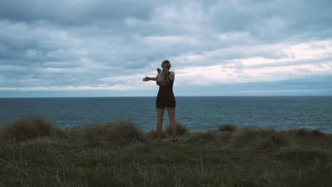 Ganzkörperaufnahme-Einer-Frau,-Die-Sich-Streckt-Und-Dabei-Den-Blick-über-Das-Meer-Genießt