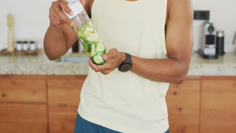 fit african american man cooking, preparing healthy green smoothie