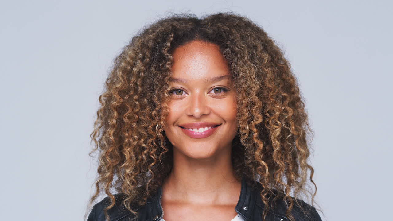 cabeza y hombros foto de estudio de una mujer con chaqueta de cuero sonriendo a la cámara en cámara lenta