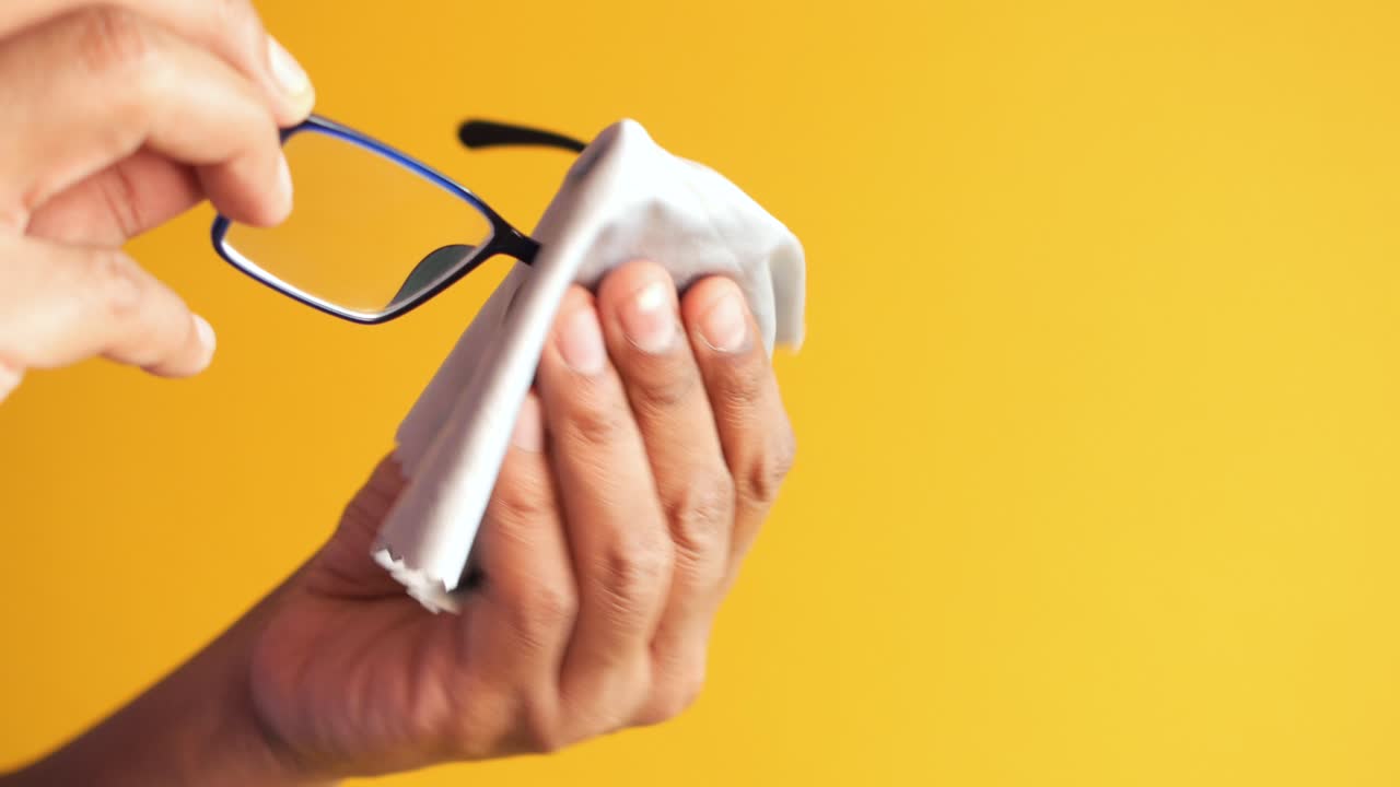 Cleaning eyeglass with tissue close up