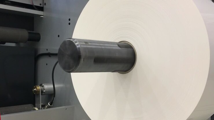Big white roll of paper in rolling machine