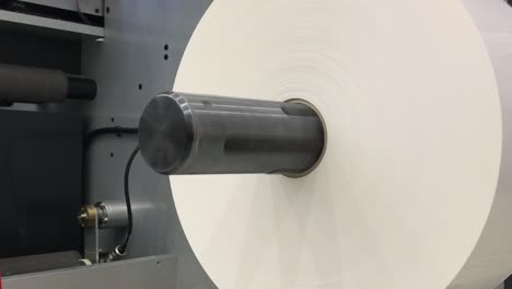 big white roll of paper in rolling machine