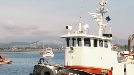 Close-up-of-a-tugboat's-bridge-or-wheelhouse-with-sirens-and-lanterns-while-being-moored-and-anchored-at-Amador's-marina-harbor-during-a-sunny-day-with-the-bridge-of-the-Americas-in-the-background