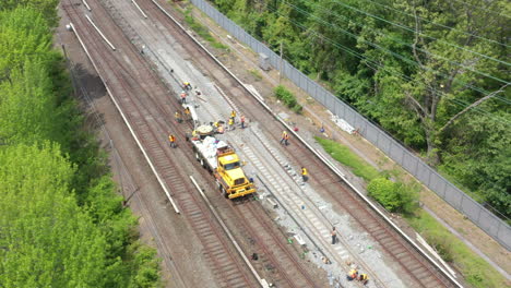 an aerial view over workers repairing train tracks on a sunny morning