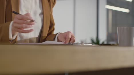 close up of businesswoman in office reviewing and making notes on application or cv for job vacancy 4