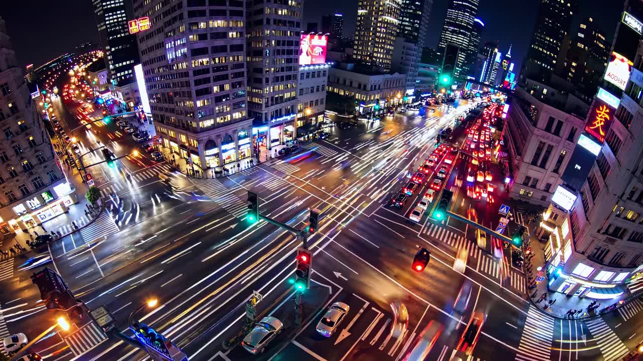 Aerial video captures a bustling city intersection at night, showcasing vibrant light trails