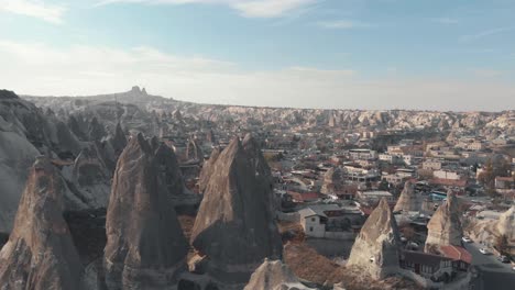 Fairy-chimney-rock-formations-in-Goreme-village,-Cappadocia-Turkey---Low-angle-orbit-aerial