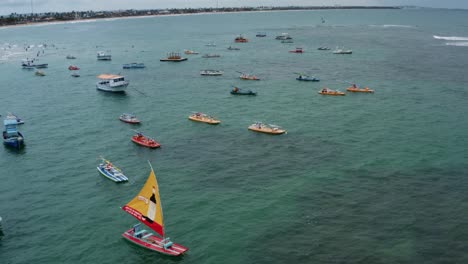 Dolly-out-Luftdrohnenaufnahme-Des-Porto-De-Galinhas-Oder-Chicken-Port-Beach-Mit-Verankerten-Segelbooten-Und-Touristen,-Die-Im-Kristallklaren-Meerwasser-In-Pernambuco,-Brasilien,-Schwimmen