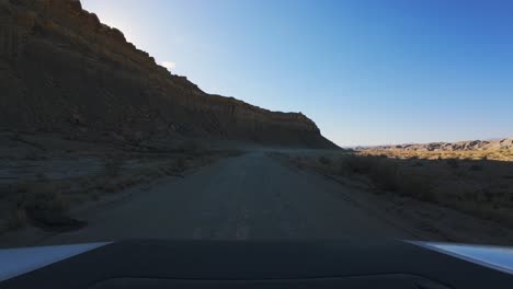 pov driving suv of factory butte road with utah's mountain range on the left