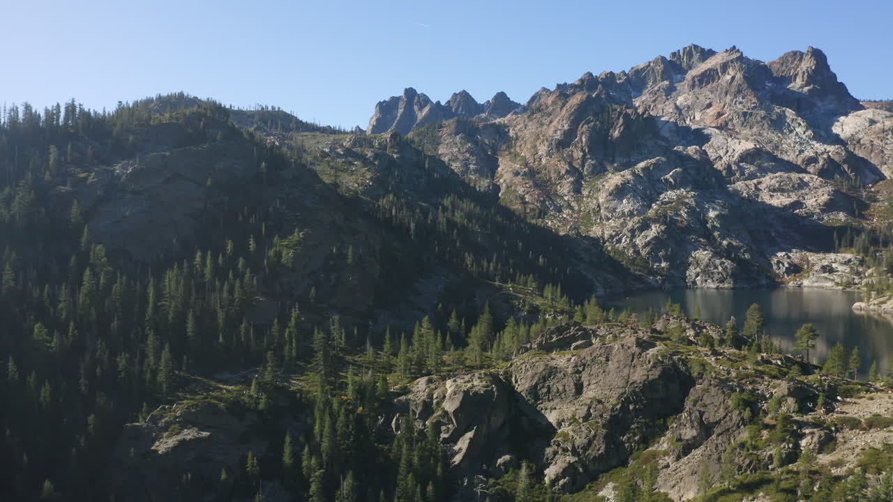 Smooth 4K drone flight over Sardine Lake in the Sierra Buttes, revealing alpine ponds, pine forest, and granite peaks in calm morning light. Peaceful, cinematic, and nature-focused aerial view