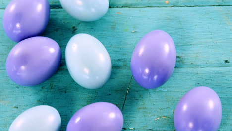 huevos de pascua pintados de azul y púrpura en superficie de madera