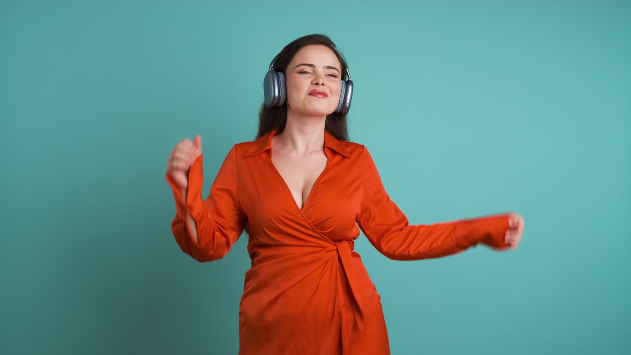 Happy woman dancing while listening to music using headphones