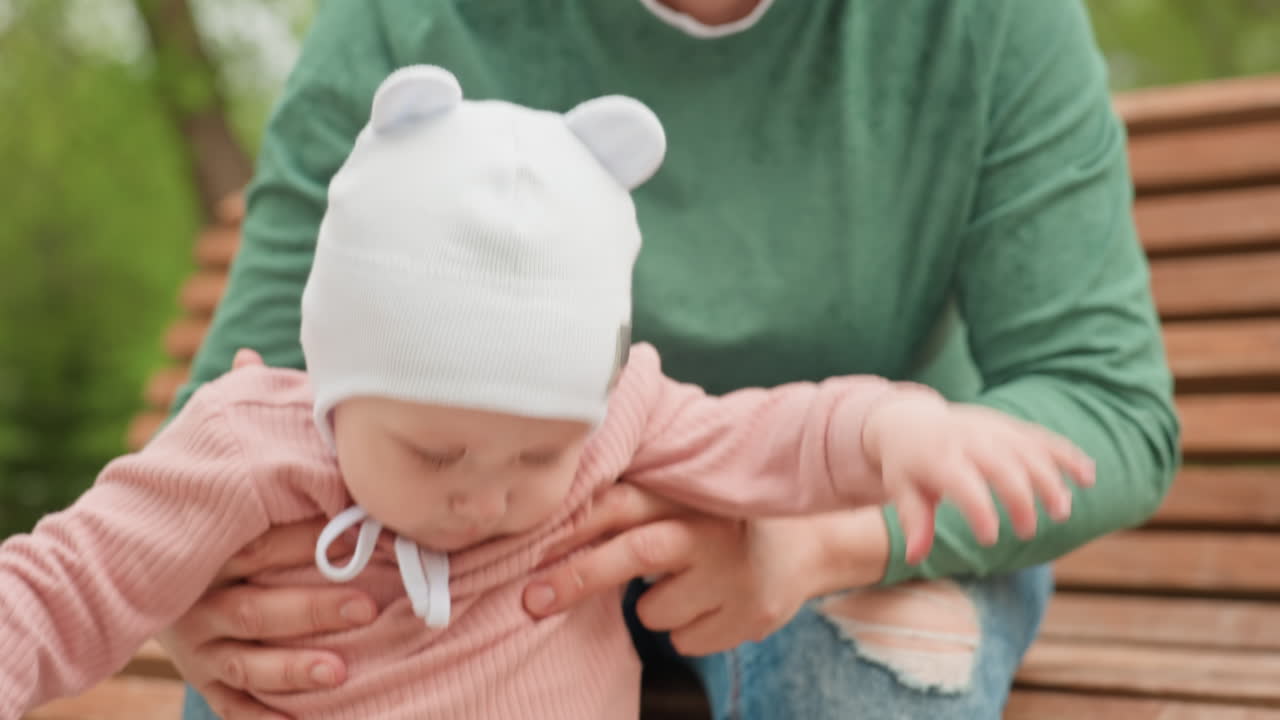 Infant Attentively Watches Toys, Young Child On Bench Carefully Focusing On Toys And Bottles, Child Sitting On Park Bench Carefully Observing And Analyzing Toys And Bottles Attentively
