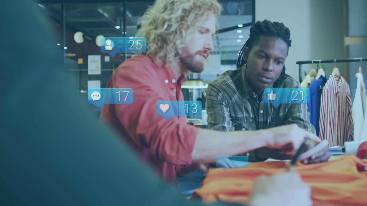 Animation of social media icons floating over two diverse male photographers discussing at studio