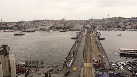 aerial drone footage of galata bridge in istanbul with a turkish flag and bosphorus and ships passing