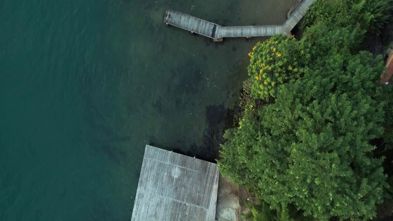vista dall'alto con un drone di una costa naturale con foresta, acqua turchese, passerelle e barche