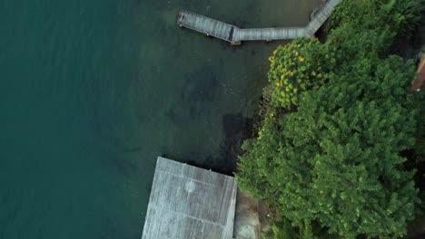 above-view-with-a-drone-of-a-natural-coast-with-forest,-turquoise-water,-boardwalks-and-boats