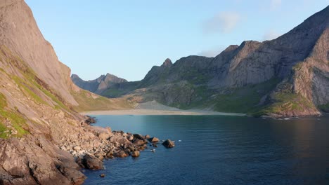 drone shot of remote horseid sand beach surrounded by steep cliffs in norway lofoten