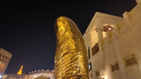 golden thumb sculpture at night in qatar