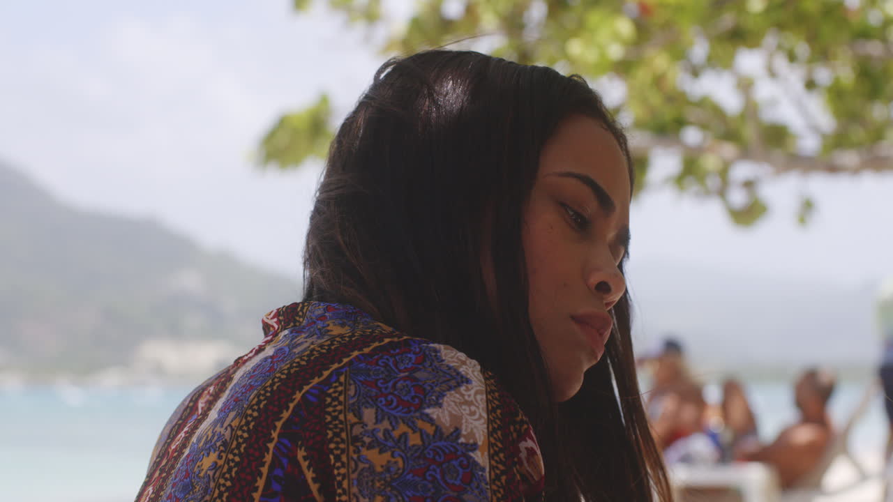 열 대 해변 독서에 라틴 여자의 초상화 샷 카메라에 미소를 머리를 돌린다