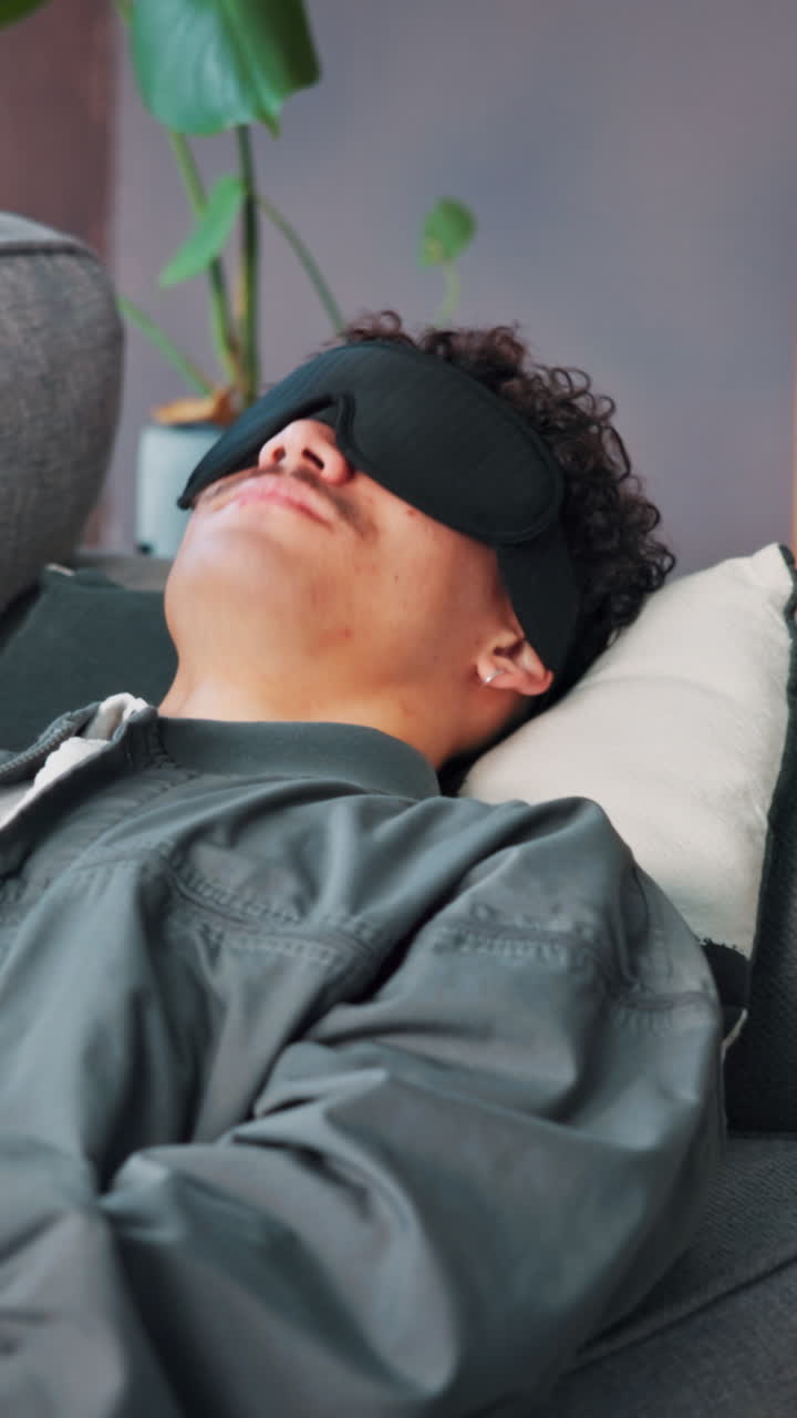 Ung mand sover fredfyldt på en sofa med en sovemaske