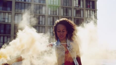 mujer joven de moda en el techo urbano usando una granada de humo