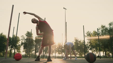 jugadores de baloncesto masculinos concentrados que se extienden en una cancha de baloncesto al aire libre