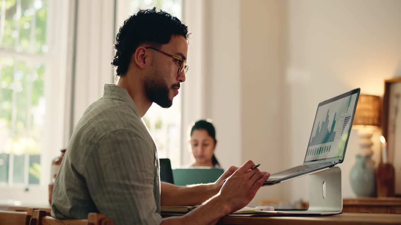 Jovem trabalhando no laptop com gráficos de dados em home office