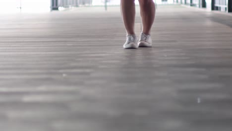 close-up of feet in sneakers performing a dynamic exercise on a wooden floor indoors.