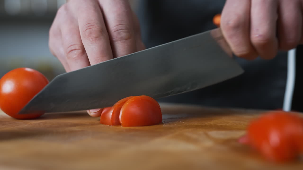 chef cortando lentamente un tomate con un cuchillo afilado grande, verduras