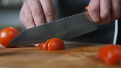 chef slowly slicing a tomato with a large sharp knife,vegetables