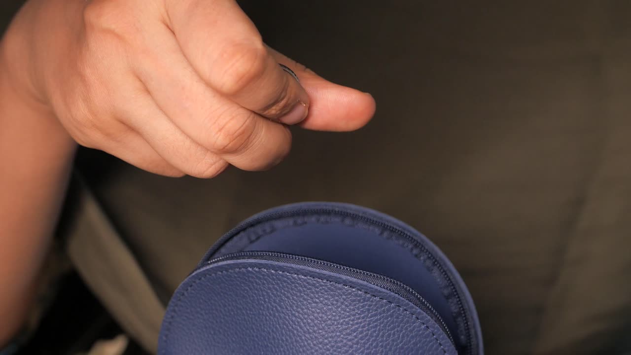 작은 파란색 가죽 가방을 열고 있는 손