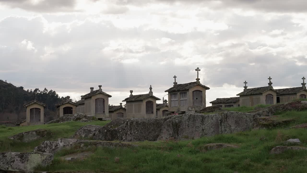 Granaries on stone platforms in Lindoso Portugal under dramatic cloudy sky
