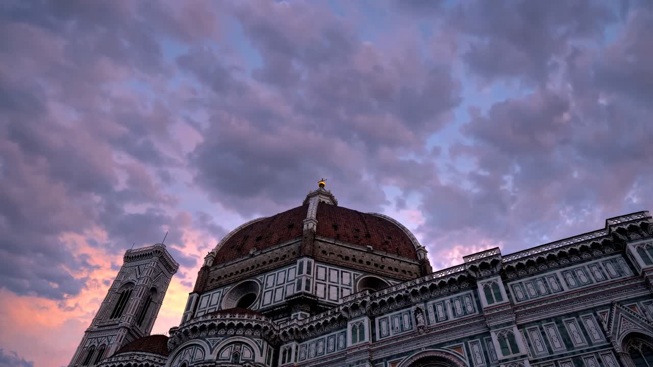 Low-angle video shot of a historic cathedral under a dramatic, cloudy sky at sunset