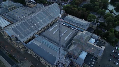 Aerial view circling above Alexandra palace glass rooftops and broadcasting mast entertainment venue