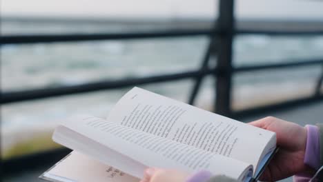 woman reading a book by the ocean