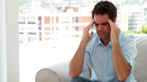 casual man sitting on the sofa getting a headache