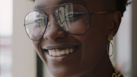 Primer-Plano-Retrato-Elegante-Joven-Afroamericana-Estudiante-Sonriendo-Feliz-Disfrutando-De-Un-Estilo-De-Vida-Exitoso-Usando-Gafas-De-Moda-Mirando-Por-La-Ventana-En-Un-Moderno-Apartamento-Loft