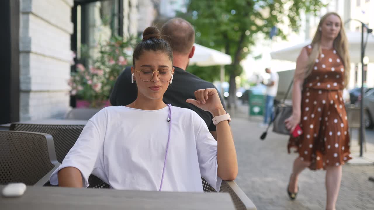 una mujer joven sentada en un café al aire libre