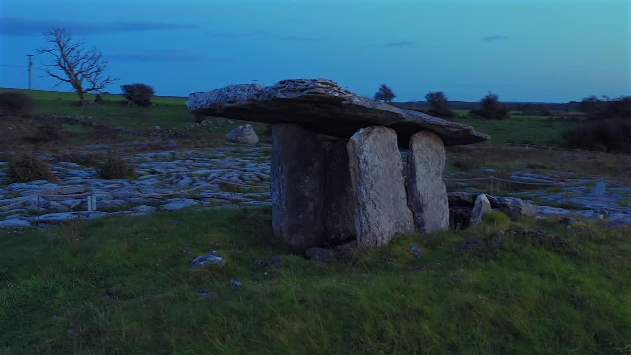 Fluido establishing shot orbitale di Poulnabrone Dolmen durante l'ora blu con la luna visibile nel cielo serale. Irlanda