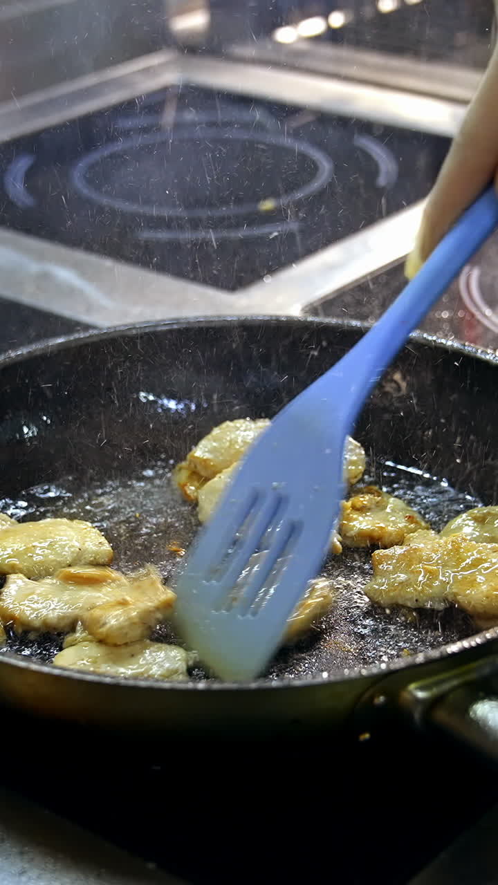 Fillet of sea white fish fried on a pan. Unrecognizible chef mixes dish with spatula. Appetizing and delicious seafood dish. Vertical video